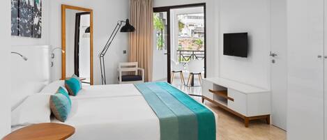 Une chambre d’hôtel moderne équipée d’un lit, d’un bureau, d’une chaise, d’une télévision et d’un balcon offrant une vue sur la ville.