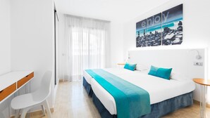 A modern hotel room with a large bed, a desk, and a window with sheer curtains. - Saint George Apartamentos      (Arona)