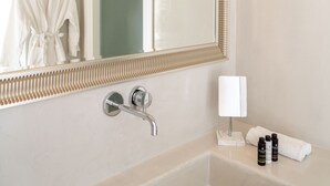Une salle de bain avec un grand miroir, une baignoire, un porte-serviettes et des articles de toilette.