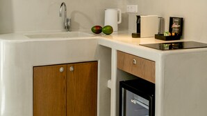 Une cuisine moderne dotée d’un évier encastré, de meubles en bois, d’une machine  à café et d’un mini-réfrigérateur.