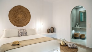 Un dormitorio con una cama grande, un tapiz tejido en la pared y un espejo con cestas.