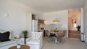 Un espacio habitable moderno y abierto, con comedor, pequeña cocina y una escalera que conduce a un nivel superior.