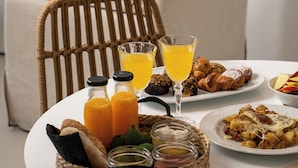 Una mesa de desayuno con croissants, zumo de naranja y una taza de café.