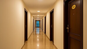 Un pasillo largo e iluminado con puertas a ambos lados, que conduce a una habitación luminosa al final.