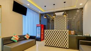 Un vestíbulo moderno de hotel con un sofá, un refrigerador de Coca-Cola y una recepción.