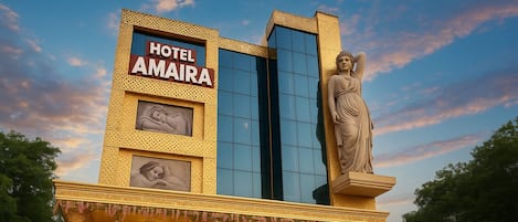 A hotel with a large statue, a sign reading "HOTEL AMAIRA," and classical architectural elements.