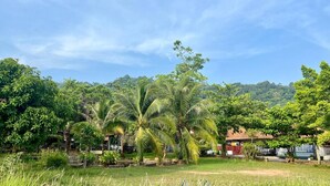 A lush green landscape with palm trees and a red-roofed building. - Valley 40 - 2 bdr Private Villa Near Phuket Town (Kathu)