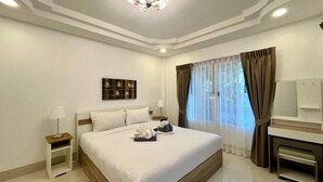 A hotel room with a large bed, a bedside table with a lamp, a TV, and a window with curtains. - Valley 40 - 2 bdr Private Villa Near Phuket Town (Kathu)