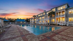 A hotel with a swimming pool, multiple balconies, and a sunset view.