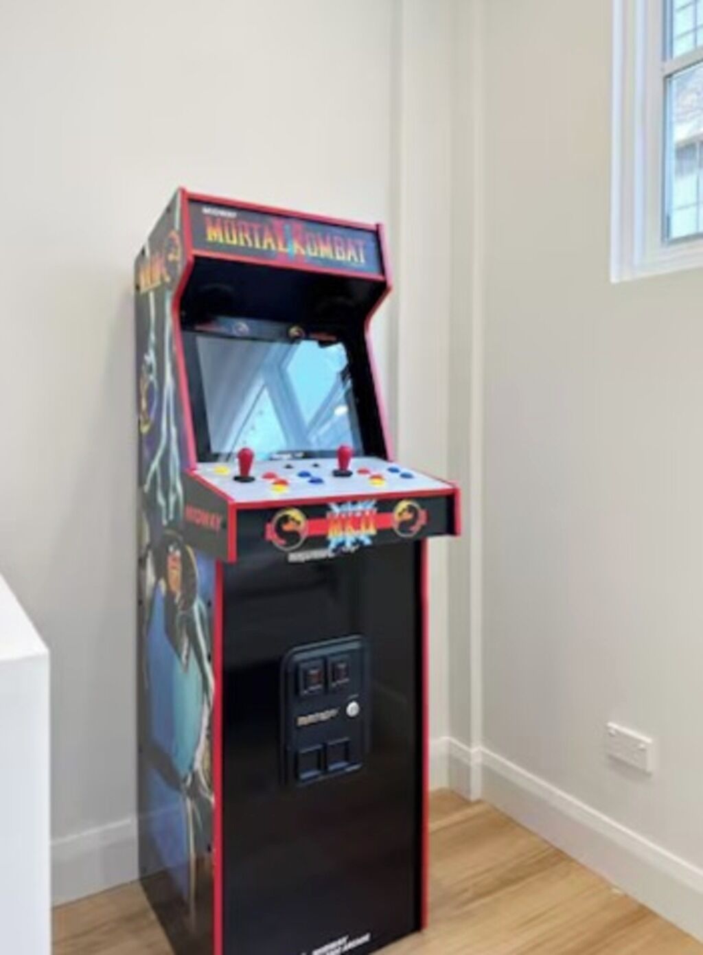 A small arcade machine with a Mortal Kombat theme, featuring a joystick and buttons on the front.