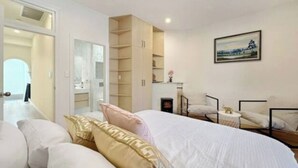 A bedroom with a large bed, a built-in wardrobe, a bedside table, and a painting on the wall.