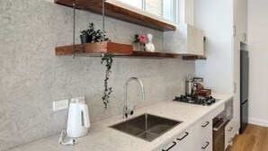 A modern kitchen with a built-in sink, wooden shelves, and a window above the counter.