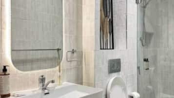 A modern bathroom with a large mirror, a sink, a toilet, and a shower area.