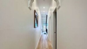 A long, narrow hallway with wooden flooring and white walls.
