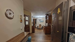 A hallway with a wooden floor, a dining area with a chandelier, and a kitchen with a refrigerator and cabinets. - Excelent 1-bed Apartment in Rzeszow (gmina Krasne)