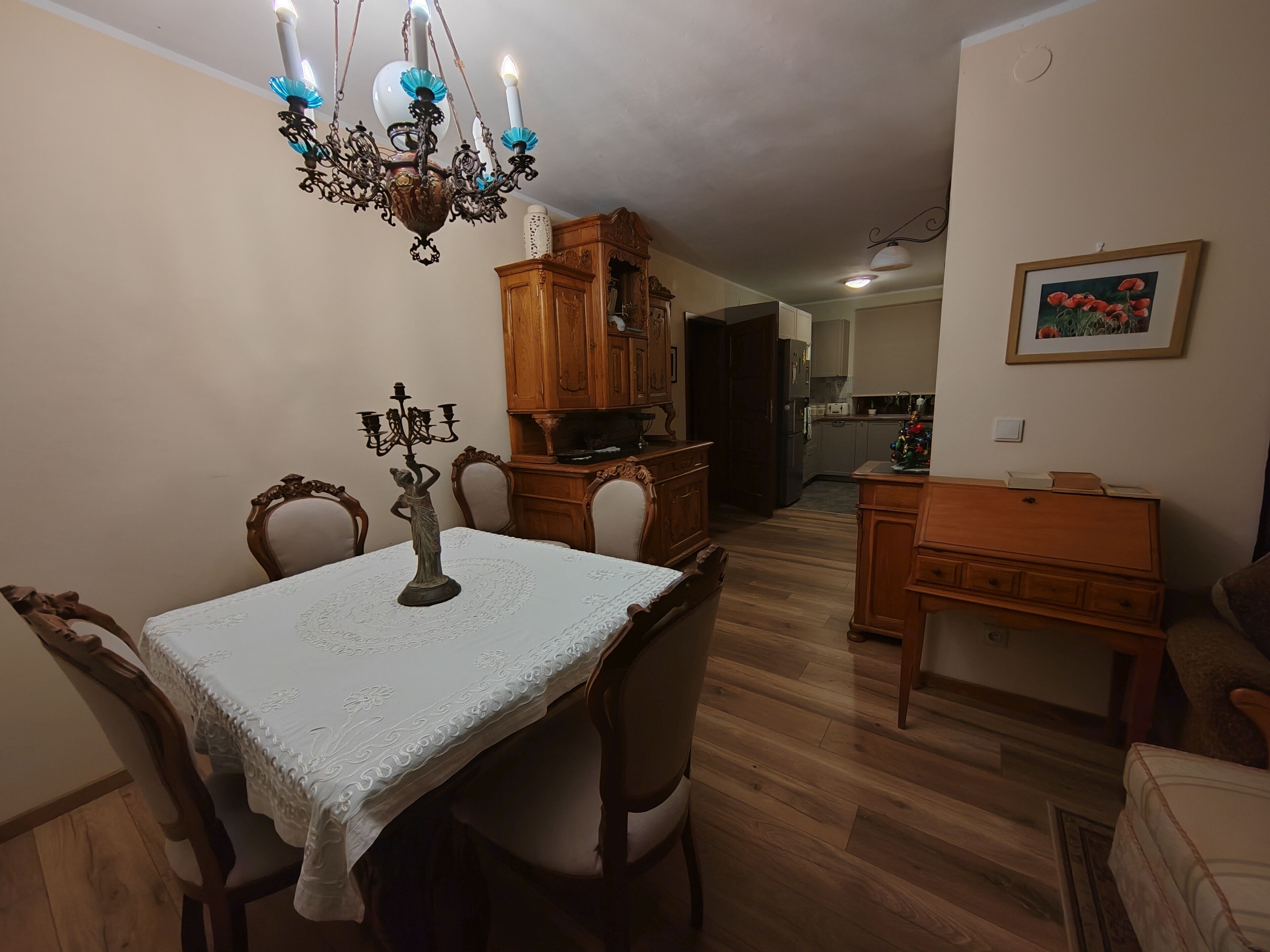 A dining area with a chandelier, wooden cabinets, and a table with chairs.