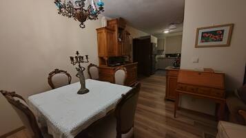 A dining area with a chandelier, wooden cabinets, and a table with chairs.