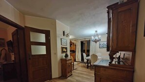 A spacious room with wooden flooring, a dining table with chairs, a chandelier, and a wooden cabinet. - Excelent 1-bed Apartment in Rzeszow (gmina Krasne)