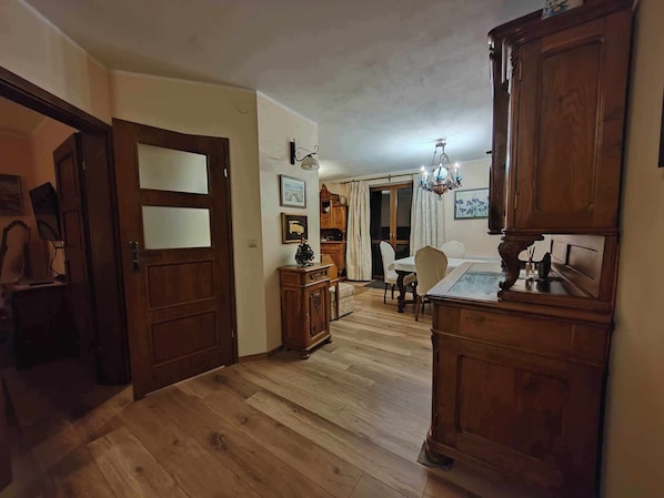 Une pièce spacieuse dotée d’un plancher en bois, d’une table à manger avec des chaises, d’un lustre et d’un buffet en bois.