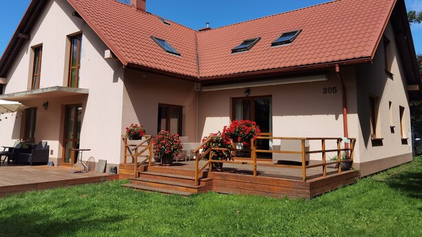 A two-story house with a red-tiled roof, a balcony with wooden railings, and a number '305' on the front wall. - Excelent 1-bed Apartment in Rzeszow (gmina Krasne)