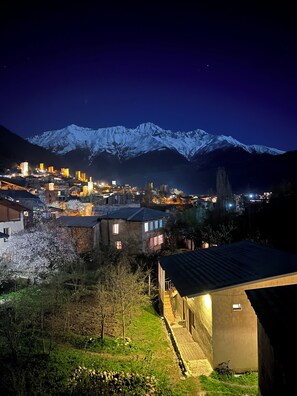 Un pueblo con edificios iluminados y una montaña nevada al fondo.
