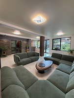A modern living room with green sofas, a wooden coffee table, and a stone accent wall.
