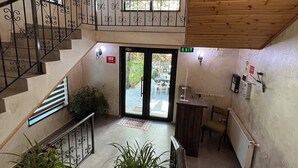 Un intérieur spacieux avec un escalier, un lustre et une vue dégagée à travers les portes vitrées.