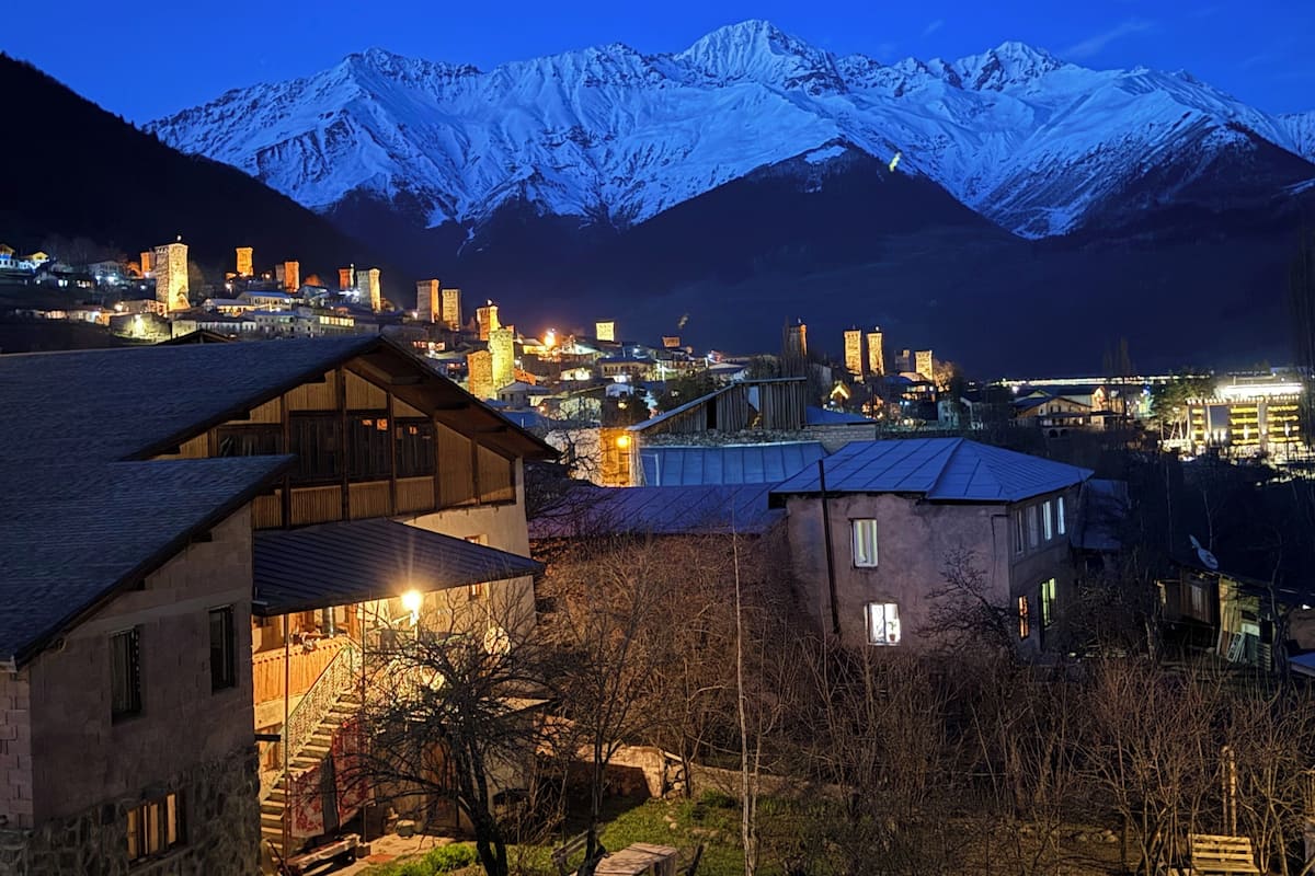 Eine Stadt mit schneebedeckten Bergen im Hintergrund, mit einer Mischung aus traditionellen und modernen Gebäuden.