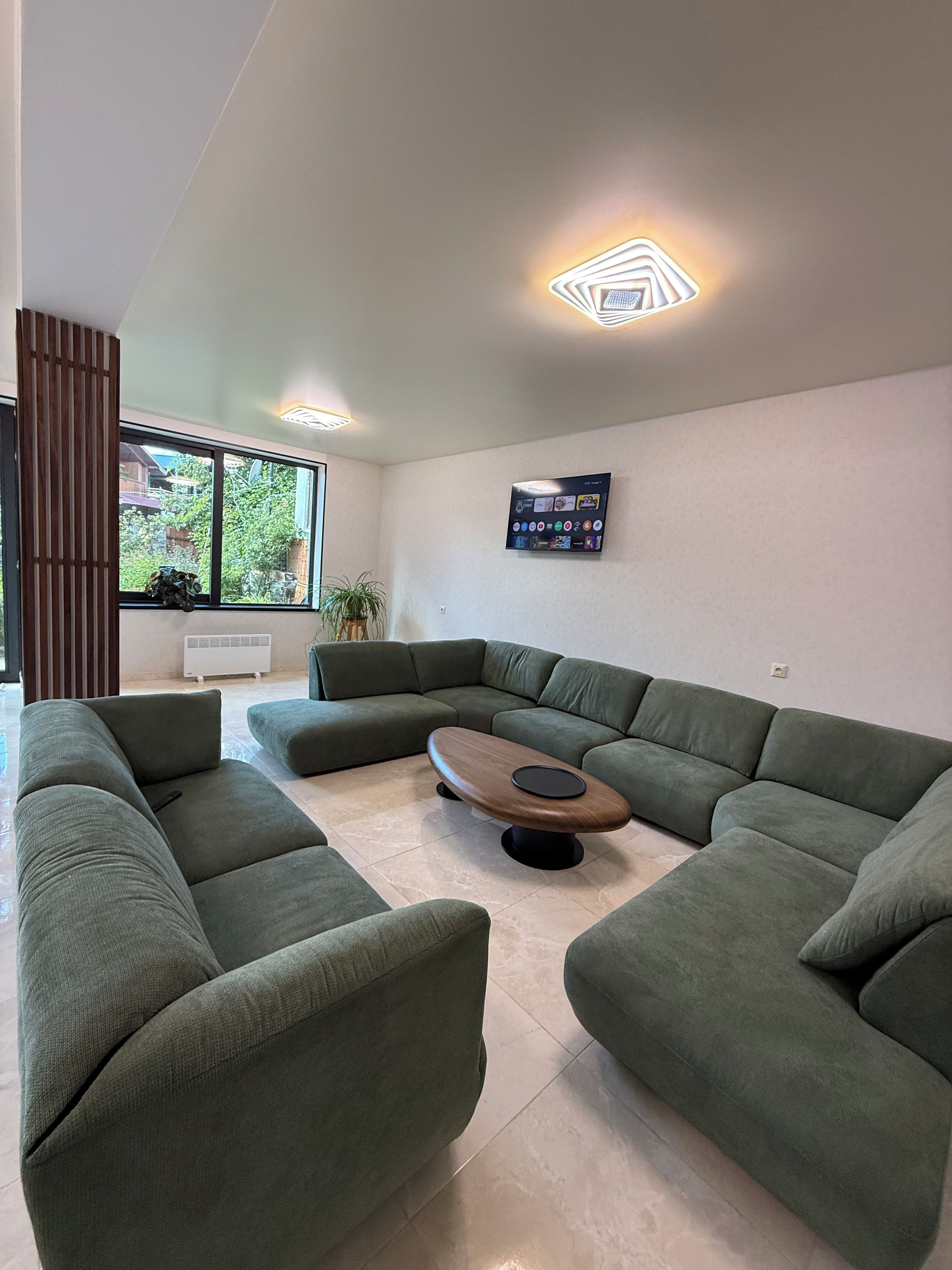 A modern living room with a sectional sofa, a coffee table, and a mounted TV.