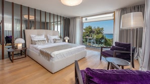 A modern hotel room with a large bed, a balcony with a view, and a seating area. - Villa Salvia (Zadar)