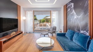 A modern living room with a flat-screen TV, a blue sofa, a round coffee table, and a large abstract painting on the wall. - Villa Salvia (Zadar)