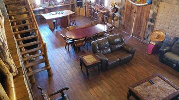 A rustic interior with a wooden dining table, leather sofa, and a staircase.