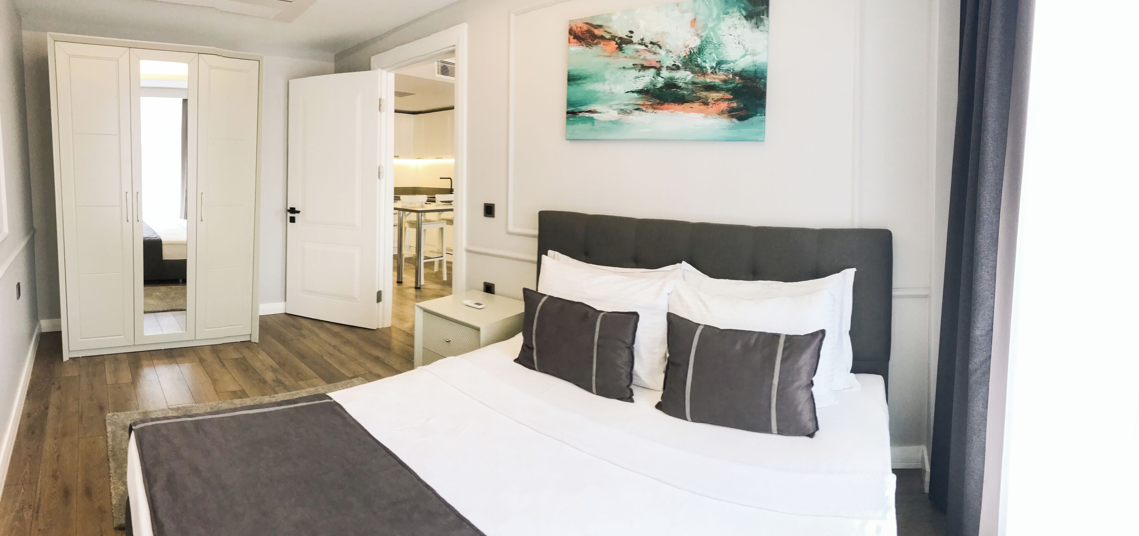 Ein Hotelzimmer mit einem Bett, einem Nachttisch, einem Kleiderschrank und einem Gemälde an der Wand.