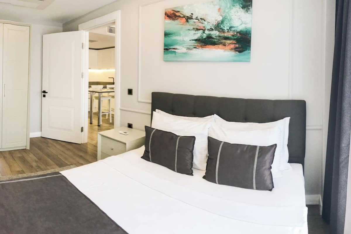 A hotel room with a bed, a nightstand, a wardrobe, and a painting on the wall.