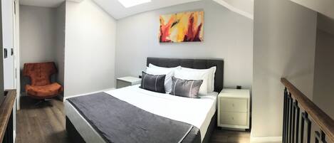 A bedroom with a bed, a nightstand, a chair, and a painting on the wall.