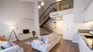 A spacious living area with a modern sofa, a dining table, and a staircase leading to an upper level. - MY WAY DELUXE HOTEL (Izmir)