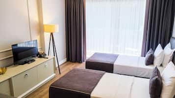 A hotel room with a bed, a TV, a desk, and a lamp.