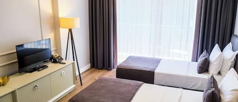 A hotel room with a bed, a TV, a desk, and a lamp.