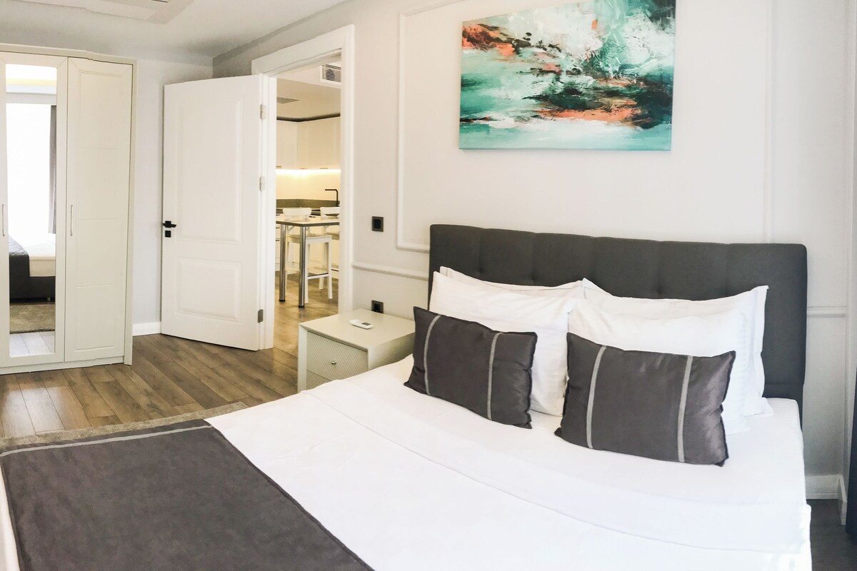 Una habitación de hotel con cama, mesita de noche, armario y un cuadro en la pared.