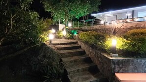 A nighttime staircase leading to a building with a green-lit entrance, surrounded by lush greenery and stone walls. - Hermosa Casa Campestre a 1 Hora de Bogotá - Tena (TENA)
