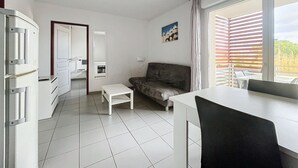 En moderne stue med sofa, spisebord og et køkkenområde med et køleskab.