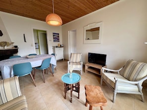 A living room with a dining area, a television, and a wooden ceiling.