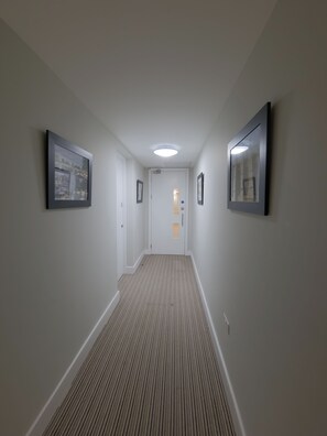 Stylish hallway with a striped carpet leading to a door, featuring framed artwork on the walls.