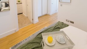 Une chambre d'hôtel moderne équipée d'un lit, d'une table de chevet avec un plateau de petit-déjeuner, d'un miroir et d'une armoire.