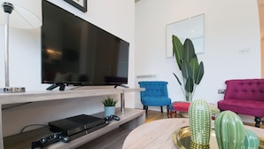Un salon moderne doté d’un téléviseur à écran plat, d’une console de jeux et d’une table basse agrémentée d’objets décoratifs.