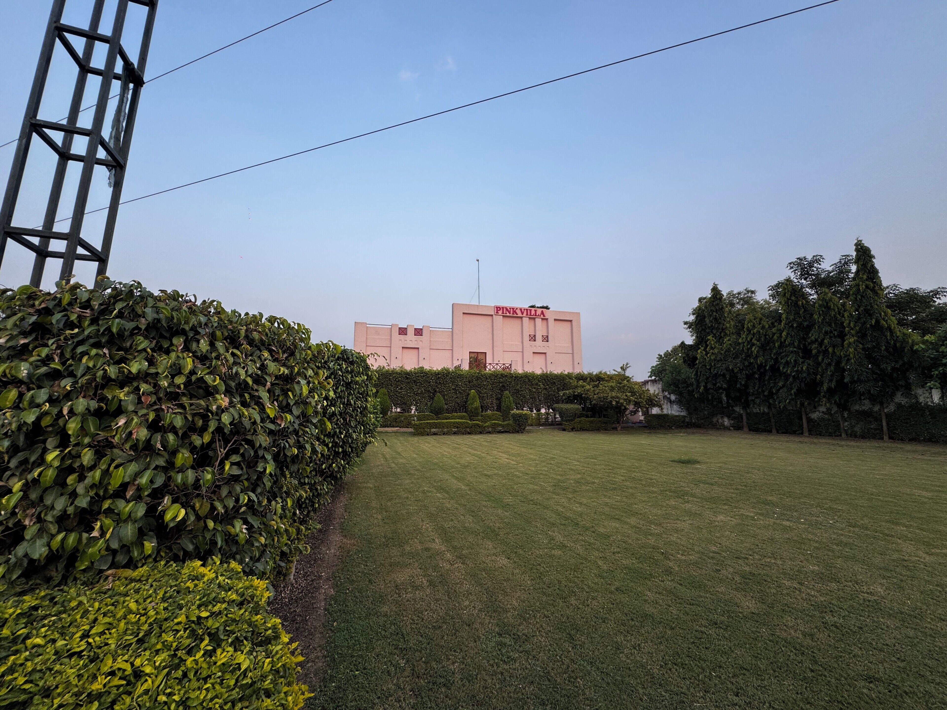 Un bâtiment appelé « VILLA ROSE », avec un ciel dégagé, une pelouse bien entretenue et une haie.