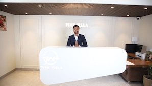En receptionsdisk med en logo, træloft og en væg med teksten "PINK VILLA".