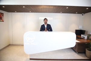 A reception desk with a logo, a wooden ceiling, and a wall with the text "PINK VILLA".