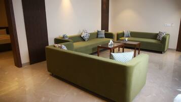 Una sala de estar moderna con sofás verdes, una mesa de centro y cojines estampados.