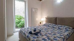Une chambre à coucher avec un lit, une fenêtre, une table de chevet et une lampe.